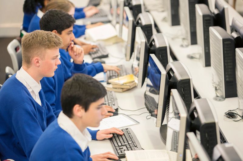 Teenage students using computers in computer room