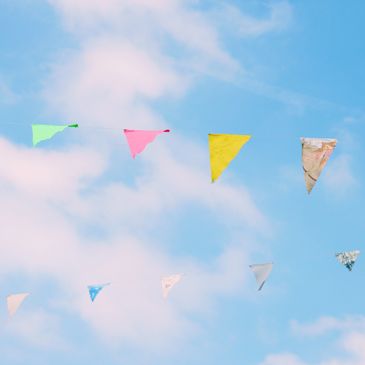 Colorful triangular flags hanging on strings against a blue sky.