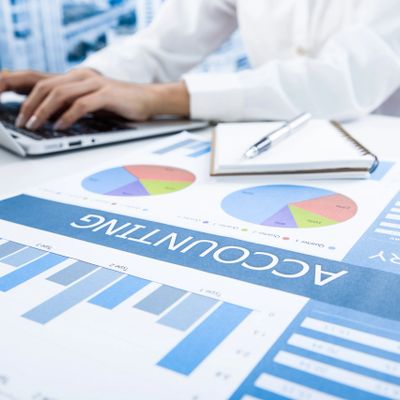 Person working on accounting with charts and graphs on desk.
