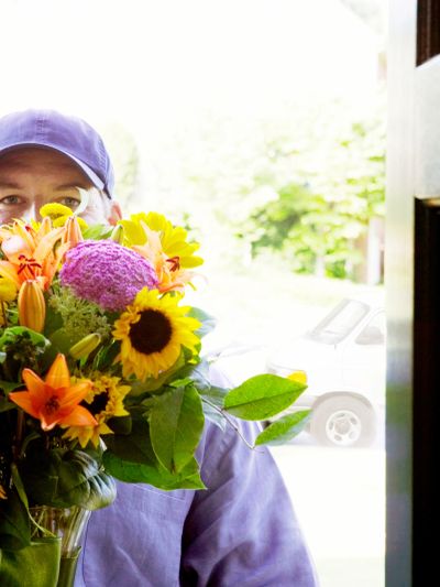 Delivery person holding a colorful bouquet at the door.