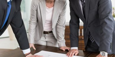 Three professionals discussing a document at a table.