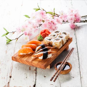 Assorted sushi served on a wooden board with chopsticks and soy sauce.