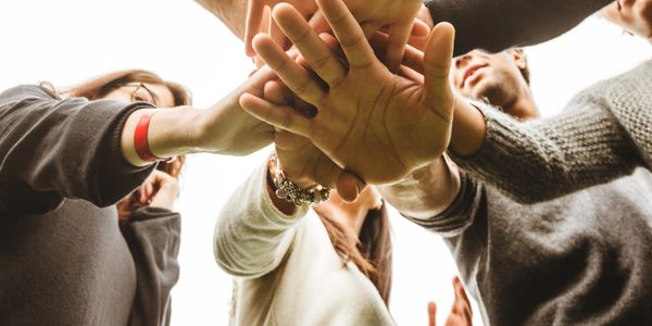 Group of people stacking hands in a team gesture.