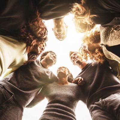Group of friends standing in a circle, arms around each other, smiling warmly.