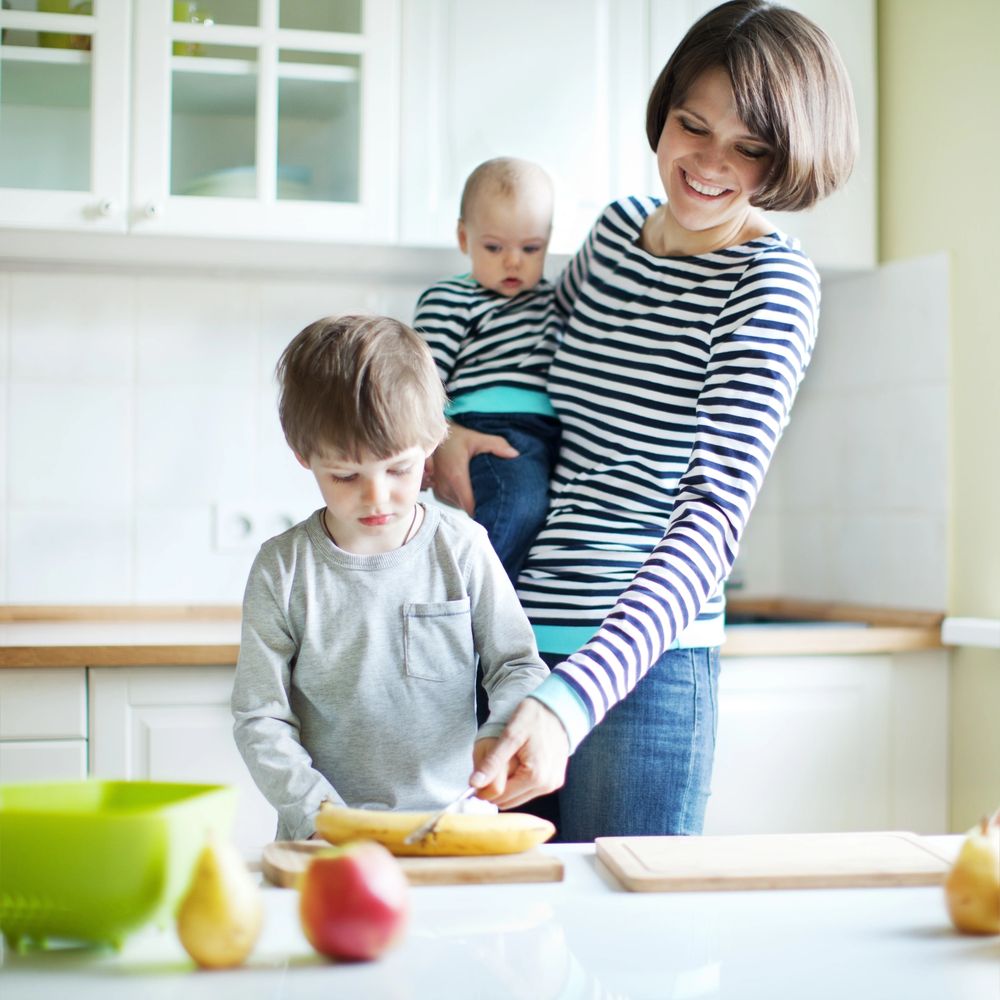 Mother with two kids preparing food in a bright kitchen.