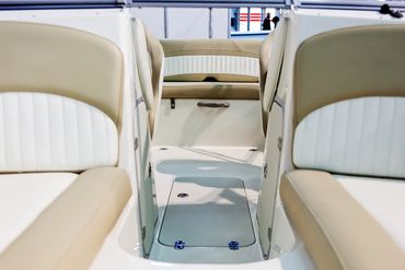 Interior seating area of a boat with beige and white cushioned seats.