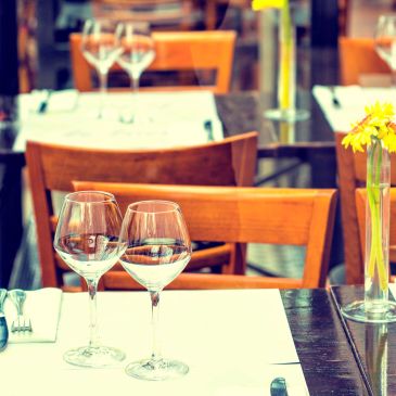 Elegant restaurant table setting with wine glasses and yellow flowers.