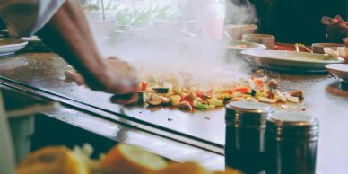 Chef cooking vegetables on a hot grill.