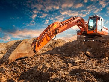 Orange excavator digging earth against a dramatic sky.