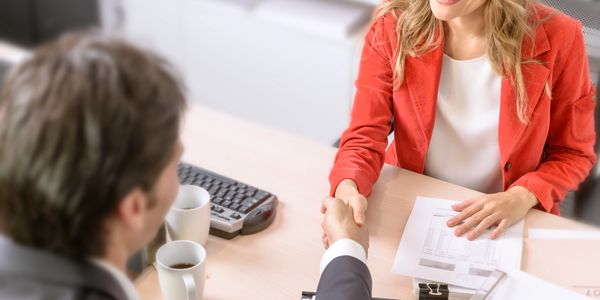 A woman shakes hands with a man while discussing finances 