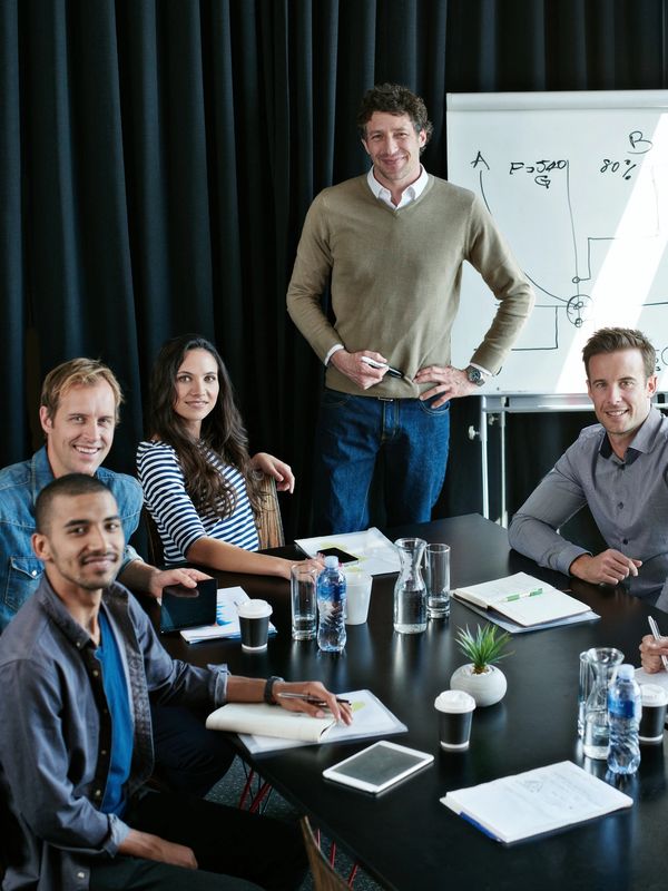 Group of professionals in a meeting room with a whiteboard.