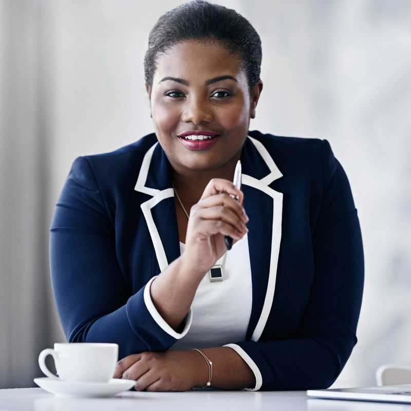 Portrait of a smiling young businesswoman sitting at a desk in an office