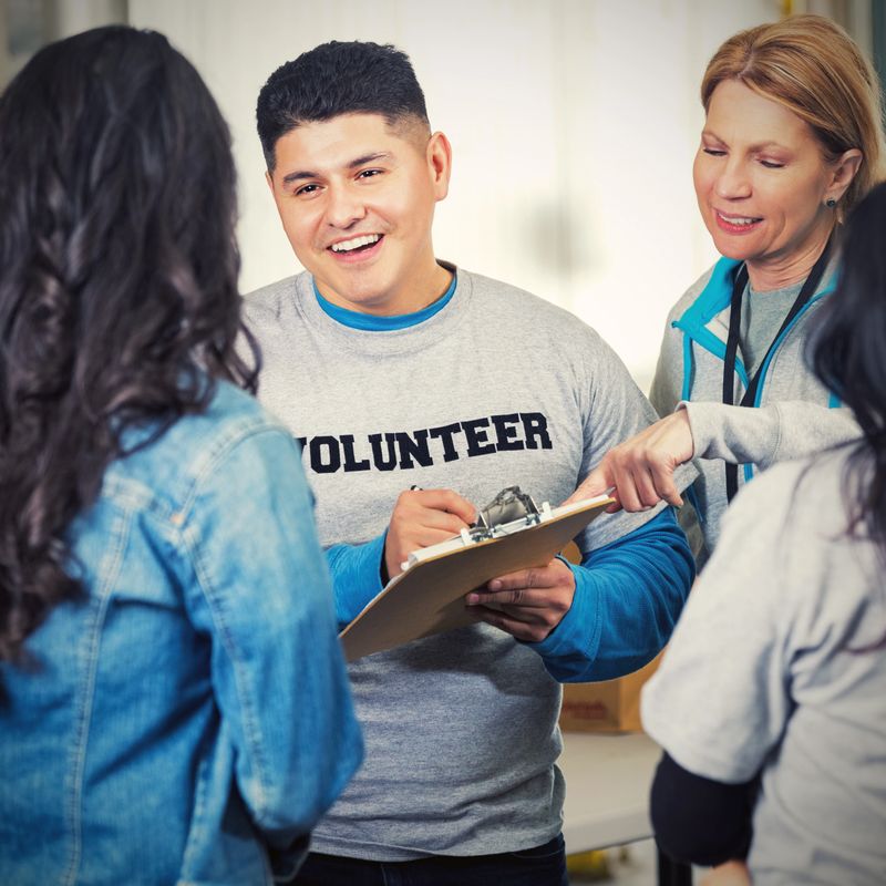 Friendly Hispanic man signing up volunteers in food bank
