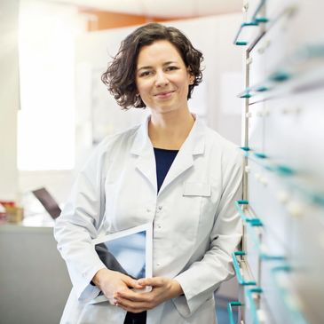 Smiling female pharmacist holding a tablet in a pharmacy.
