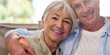 Smiling elderly couple embracing on a couch.