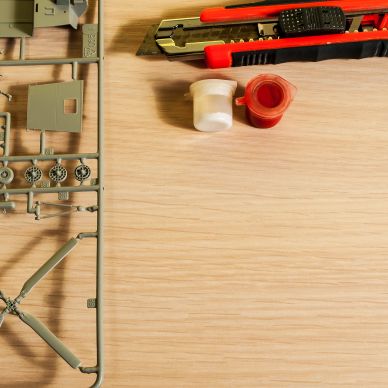 Materiali per modellismo con taglierine e vernici su sfondo di legno.