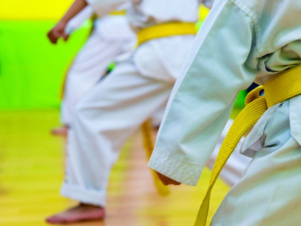 Kids practicing martial arts with yellow belts in a dojo.