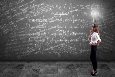 Woman thinking in front of a wall covered with mathematical formulas.