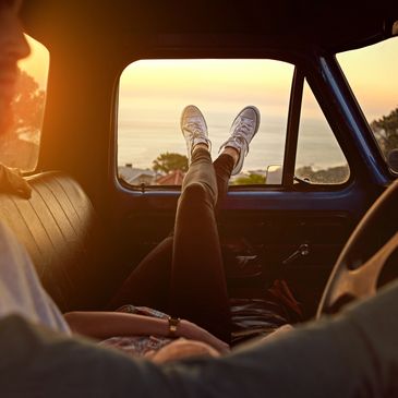 Person relaxing inside a vehicle, legs stretched out toward a sunset view.