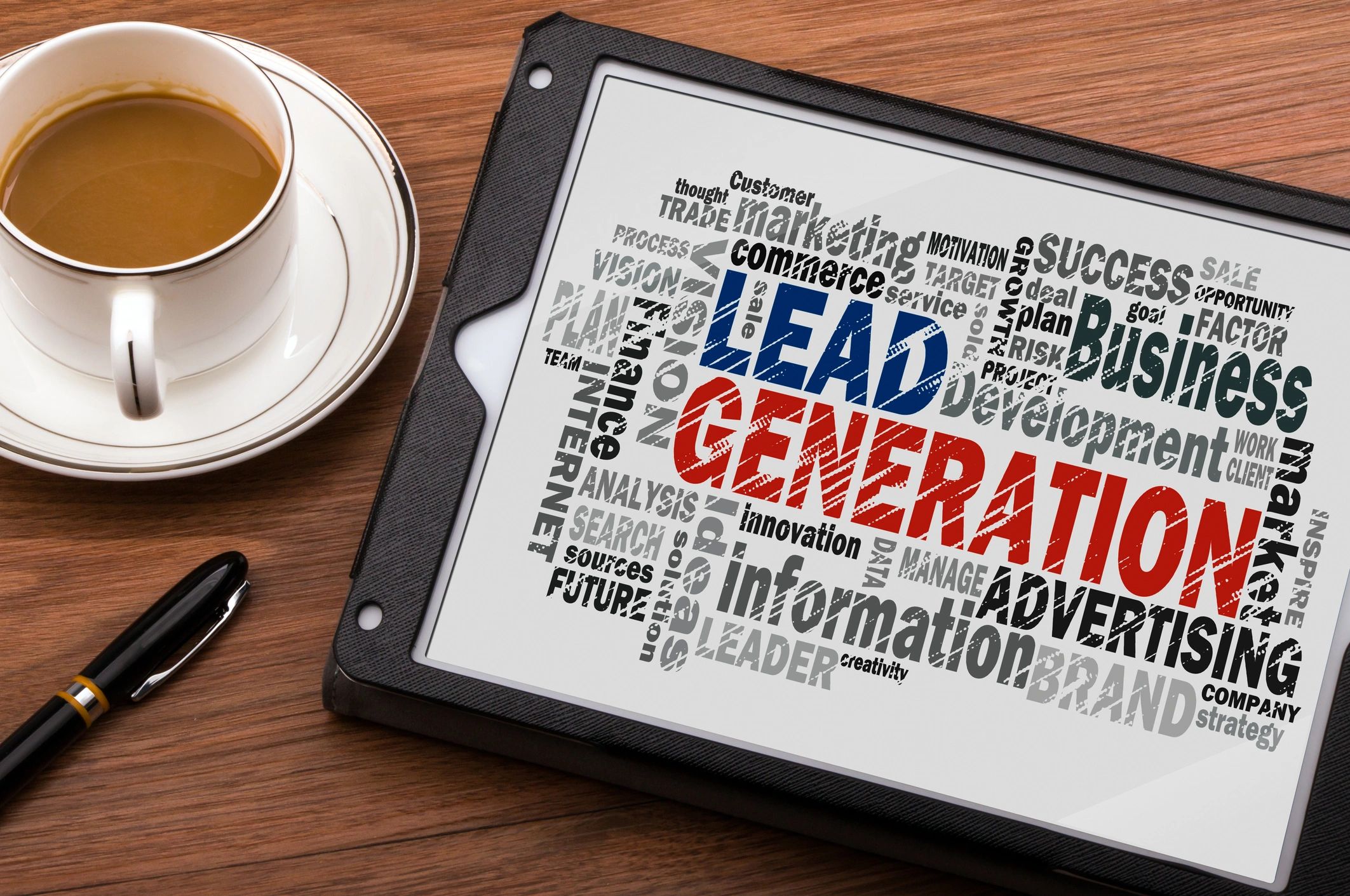 Tablet displaying lead generation word cloud next to coffee and pen on wooden table.