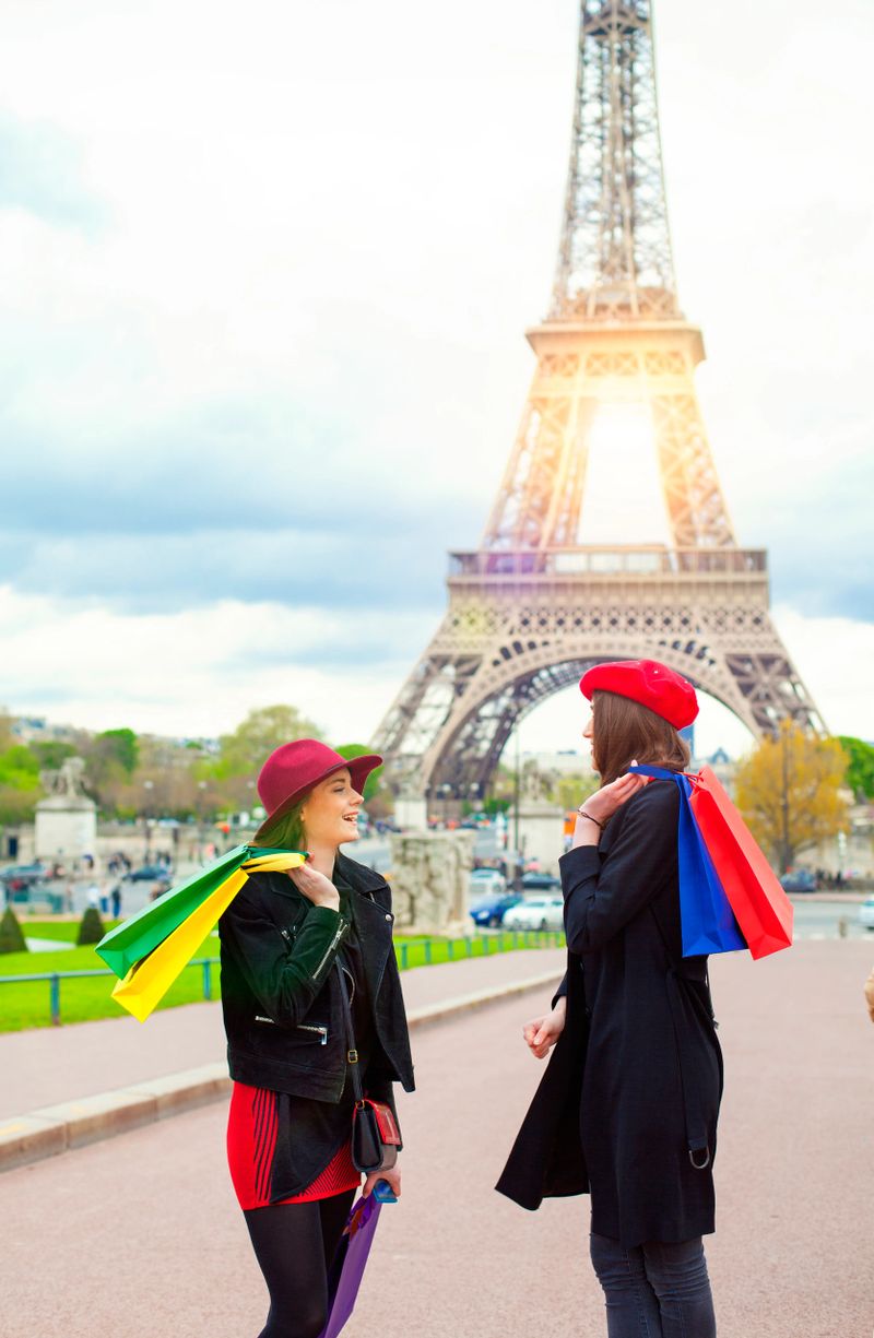 Two beautiful young women with shopping bags  on the Eiffel Tower in Paris, France with colorful bags. 