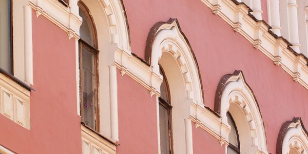 Close-up of ornate arched windows on a pink building facade.