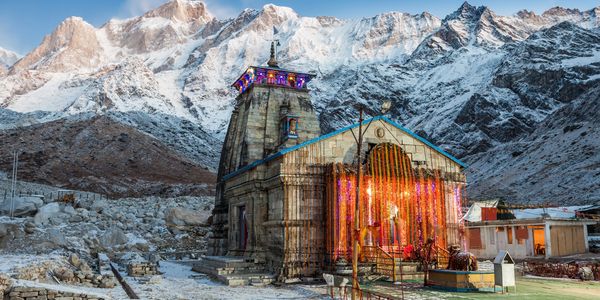 Ancient temple decorated with lights against snowy mountains.