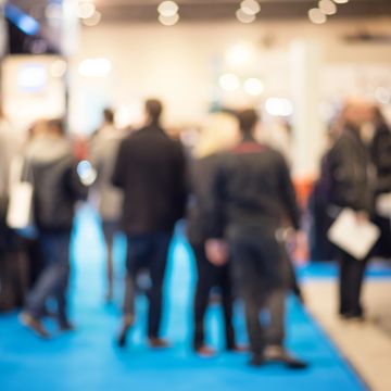 Blurry crowd walking on a blue carpet indoors.