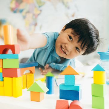 Smiling child playing with colorful building blocks.