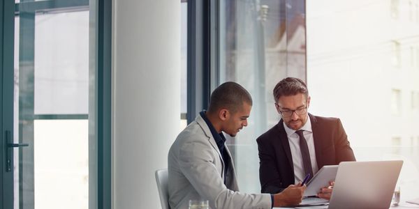 Two businessmen reviewing documents together in a modern office.