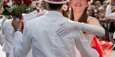 A couple dances in white attire during a festive outdoor event.