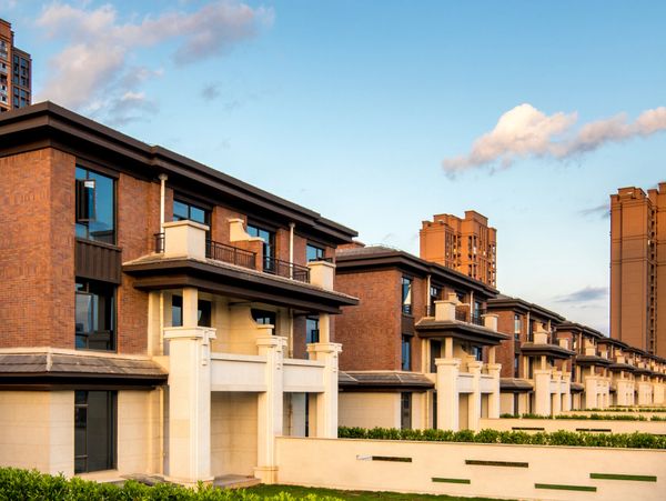 Row of modern townhouses with brick and beige exteriors under a blue sky.