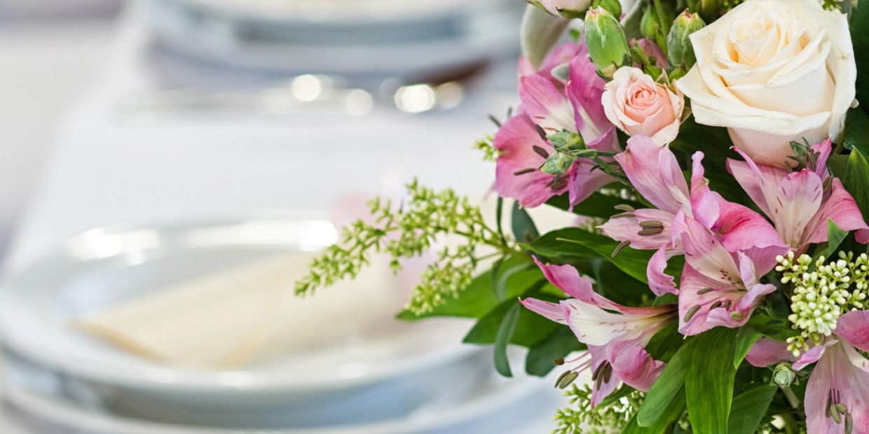 Elegant floral centerpiece with pink and white flowers on a formal dining table.