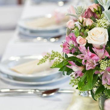 Elegant table setting with a floral centerpiece featuring pink and white flowers.