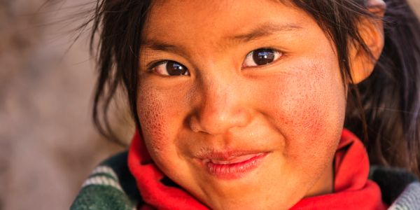 Close-up of a smiling girl with rosy cheeks and dark hair.