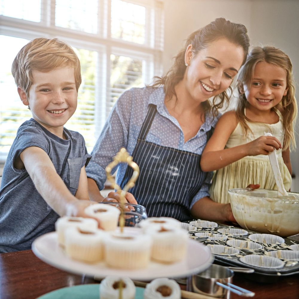 A happy family baking cupcakes together in a bright kitchen.