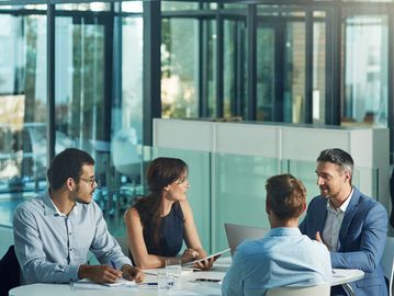 Four professionals engaged in a discussion around a white table in a modern office.