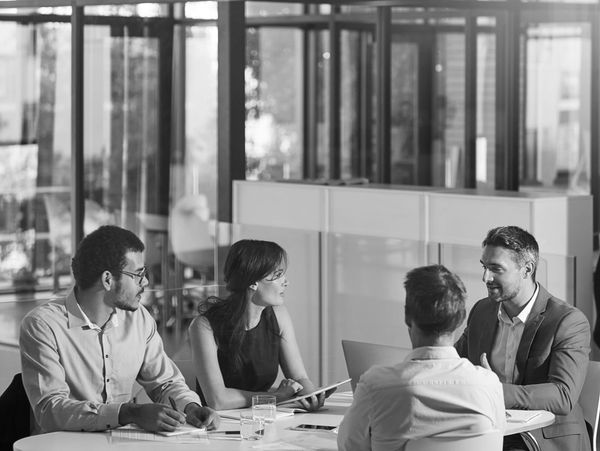 Four professionals engaged in a discussion around a table in a modern office.