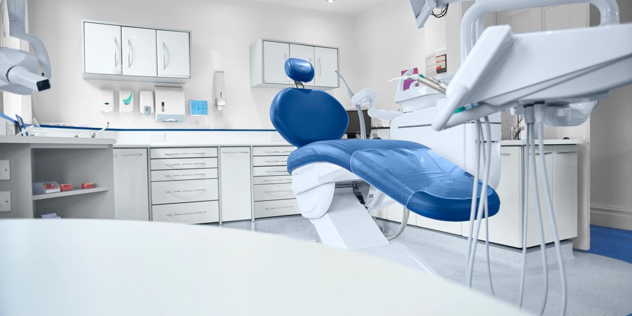 Modern dental clinic room with blue dental chair.