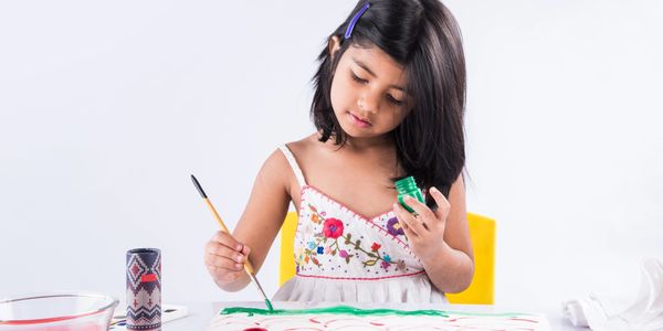 Young girl painting with green color on paper, focused and creative.
