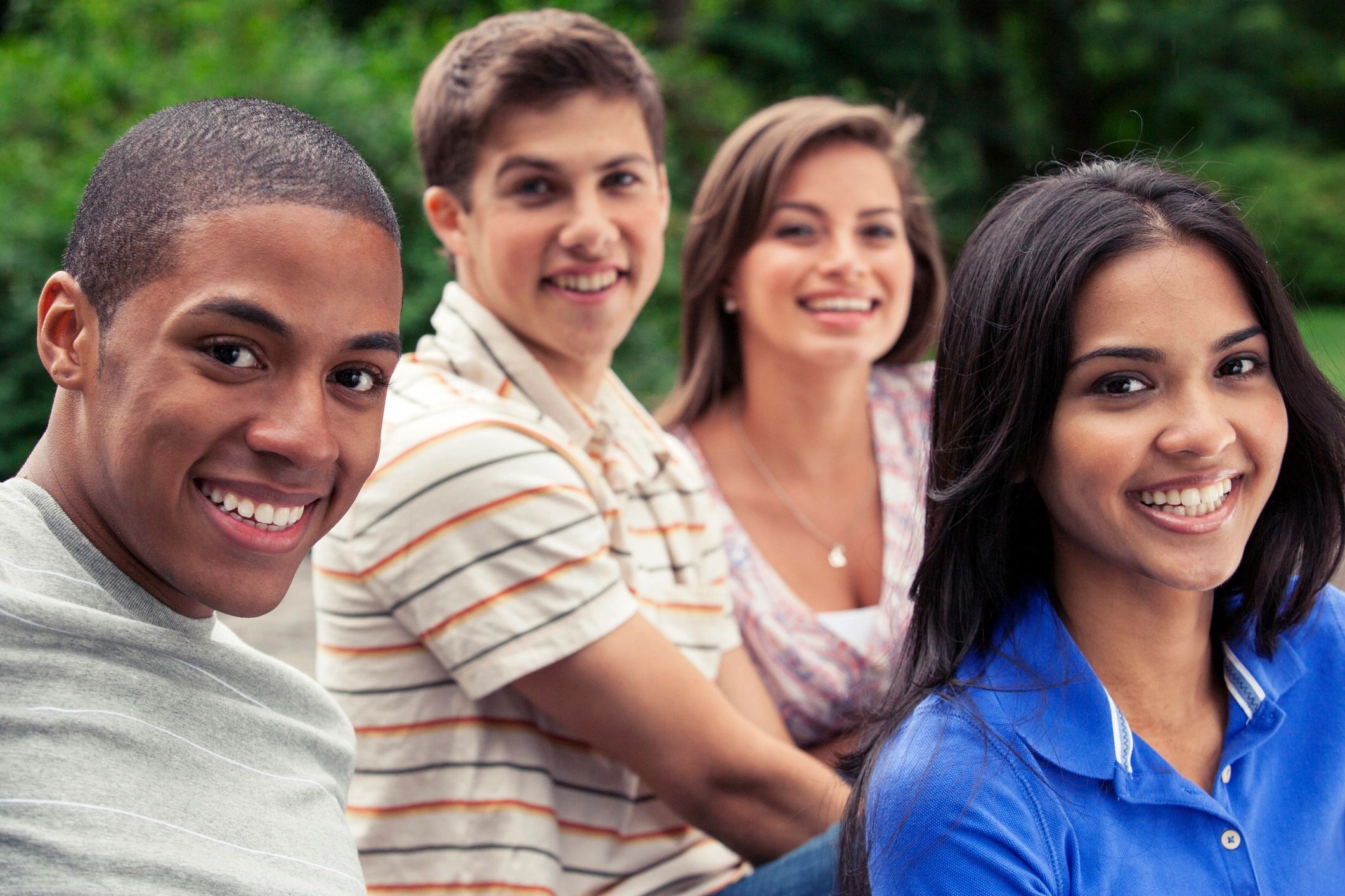 Four young friends smiling outdoors.