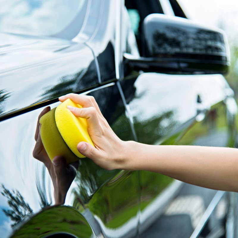 Woman hand polishing her black car.