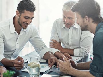 Three men collaborating over a tablet in an office.