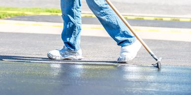 Person smoothing freshly laid asphalt on a road.