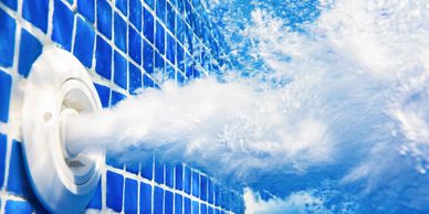 Water jet shooting bubbles inside a blue-tiled pool.