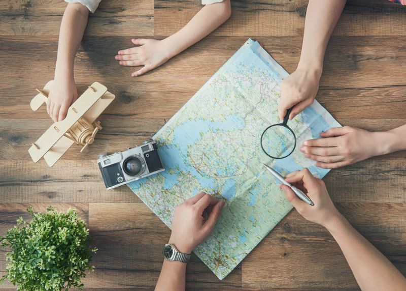 Go on an adventure! Happy family preparing for the journey. Mom, dad and daughter study the map and choose a route of travel.