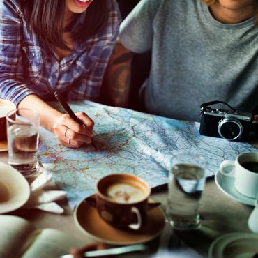 Two people planning a trip with a map, coffee, and a camera on the table.