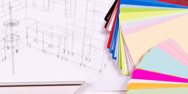 Color swatches fanned out next to architectural blueprints on a desk.