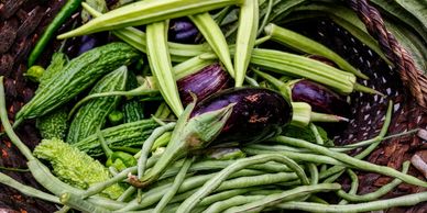 A basket full of fresh vegetables including green beans and eggplant.