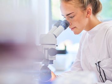 Mujer observando por un microscopio en un laboratorio.